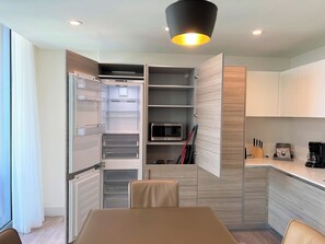 A modern kitchen with a built-in microwave, a coffee maker, and a dining area with a table and chairs.