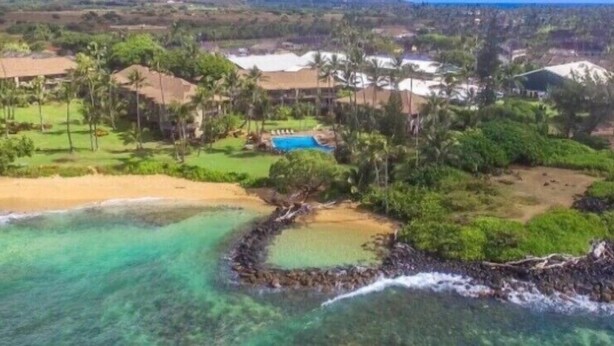 Luchtbeeld van een resort met meerdere gebouwen, een zwembad en een strandgebied.