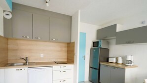 A compact kitchen with white and grey cabinets, a stainless steel refrigerator, a microwave, and a coffee maker. - Appartement Résidence le Casino à Perros Guirec (PERROS GUIREC)