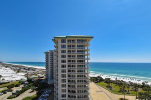 Un hotel de gran altura con múltiples balcones con vistas a una playa y al océano.