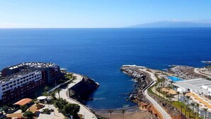 A coastal resort with a rocky shoreline, a swimming pool, and a view of the ocean.