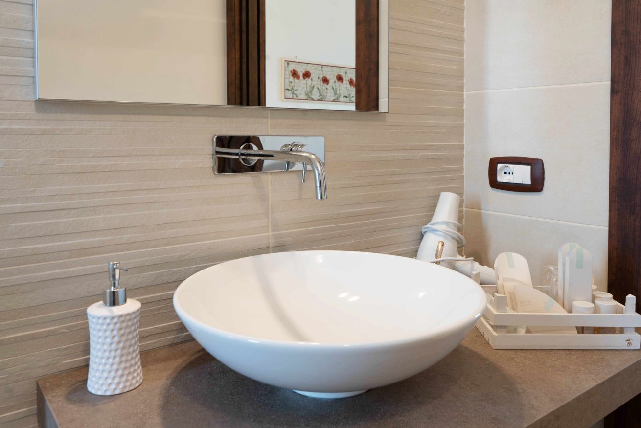 A bathroom with a large white sink, a mirror above it, and a towel rack with toiletries.