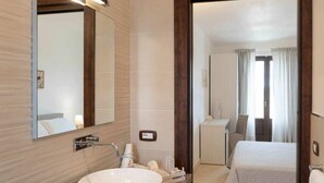 A modern bathroom with a large sink, mirror, and a visible shower area.