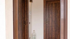 A hallway with a wooden door and a white lantern on the floor.