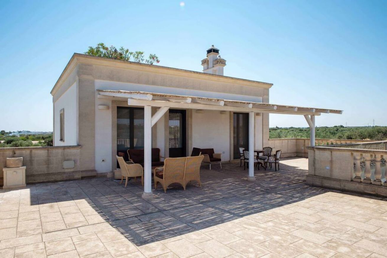 A rooftop patio with outdoor furniture, a pergola, and a view of the landscape.