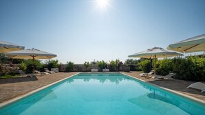A clear blue pool with lounge chairs and umbrellas, surrounded by greenery. - TERRA TERRA - Masseria Minunni - Suite C.Tartara (Conversano)