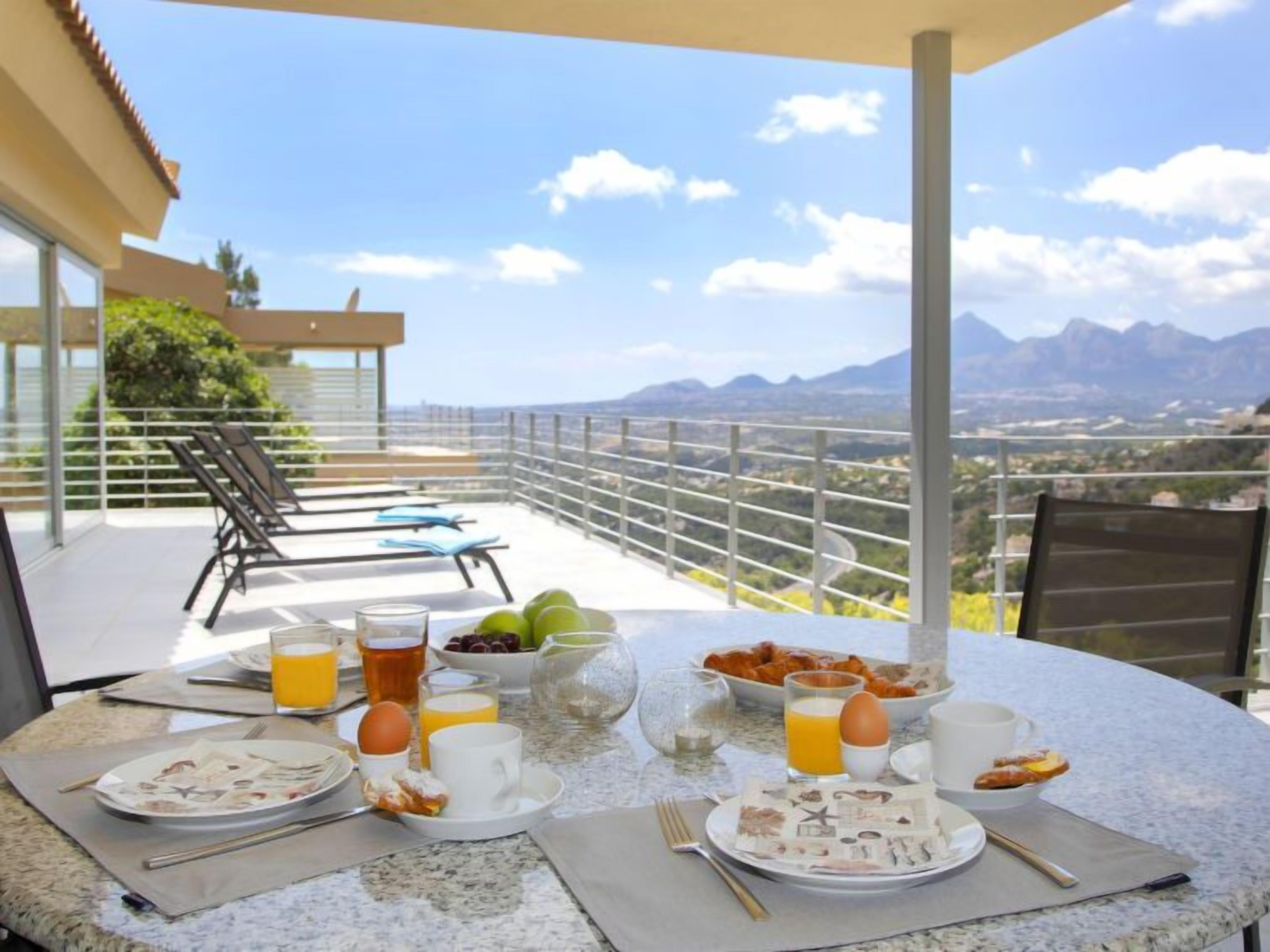 A breakfast table set on a balcony with a scenic mountain view.