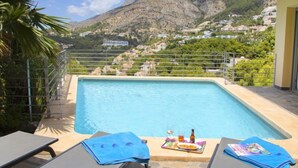 A swimming pool with a mountain view, a table with a drink and snacks, and lounge chairs. - La Estrella by Interhome (Altea)