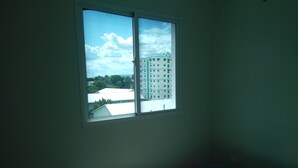 A room with a window overlooking a building and trees.