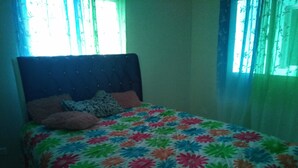 A bed with a floral bedspread, a headboard, and pillows.