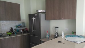 A kitchen with wooden cabinets, a stainless steel refrigerator, a blender, and a sink.