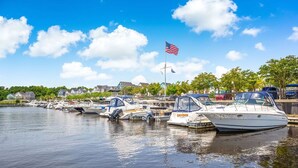 A marina with several boats docked, a flagpole with an American flag, and houses in the background. - 🏝 Barefoot Landings in N Myrtle Beach-2 Resort Pools/ Golf/  8 Mins to Beach 🏝 (North Myrtle Beach)