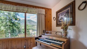 Un piano se trouve dans une pièce aux murs en bois, avec une grande fenêtre donnant sur une zone boisée.