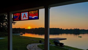 A lakeside view from a covered porch with a stone pathway leading to a dock. - Peaceful Private Waterfront Home (Redwood)
