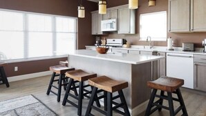 A modern kitchen with a large island, bar stools, and pendant lighting. - Peaceful Private Waterfront Home (Redwood)