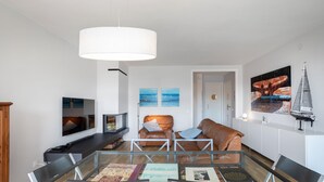 Un salón moderno con una mesa de centro de vidrio, sofás de cuero y una lámpara colgante blanca de gran tamaño.