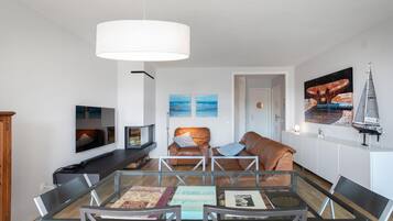 Un salón moderno con una mesa de centro de vidrio, sofás de cuero y una lámpara colgante blanca de gran tamaño.