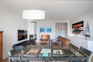A modern living room with a glass coffee table, leather sofas, and a large white pendant light. - BAIX BALIS accommodation for families. Beach 5 minutes walking (Sant Andreu de Llavaneres)