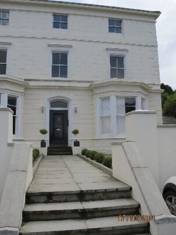 A white building with a symmetrical facade, a central entrance with a black door, and a set of stairs leading up to it. - Private luxury apartment near Belfast with garage (Holywood)
