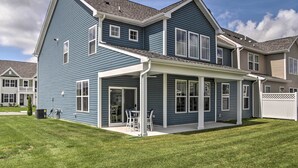 Une maison à deux étages avec un patio couvert et une pelouse.
