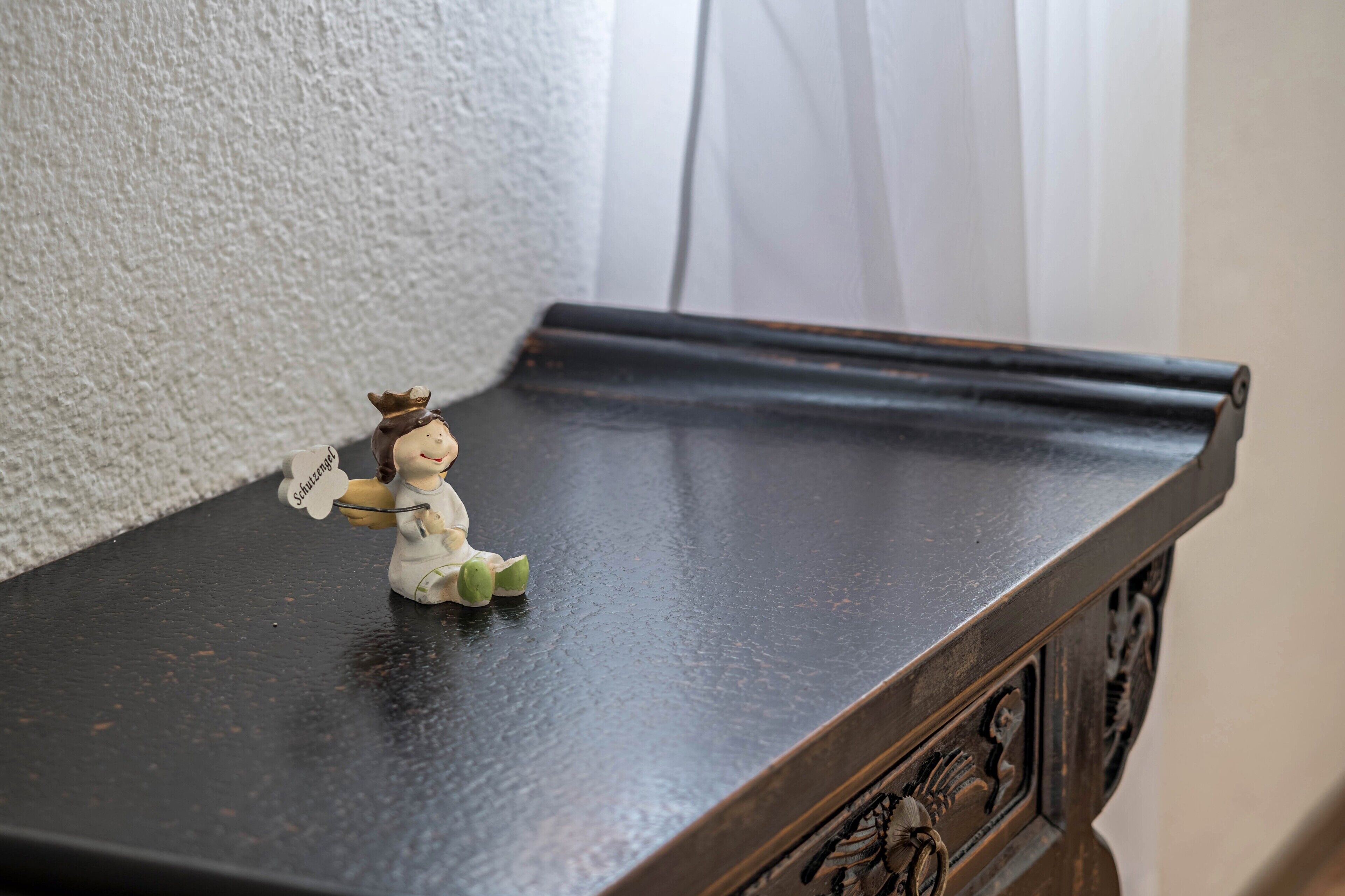 Une petite figurine posée sur une table en bois foncé.