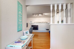A modern living room with a fireplace, a staircase, and a wall-mounted sign.
