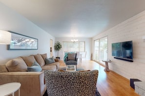 A modern living room with a sofa, armchair, and a flat-screen TV mounted on the wall.