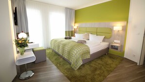 A hotel room with a bed, bedside tables, a mirror, and a green accent wall. - Single room in category M - Hotel Am Kaisersaal (Erfurt)