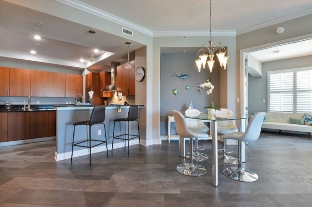 A modern kitchen with a central island, bar stools, and pendant lighting.