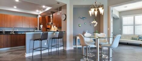 A modern kitchen with a central island, bar stools, and pendant lighting.