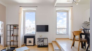 Ein modernes Wohnzimmer mit Flachbildfernseher, Kamin, Essbereich mit einer Bank und Bücherregal.