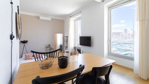 Ein moderner Essbereich mit Holztisch, schwarzen Stühlen und einem an der Wand befestigten Fernseher.