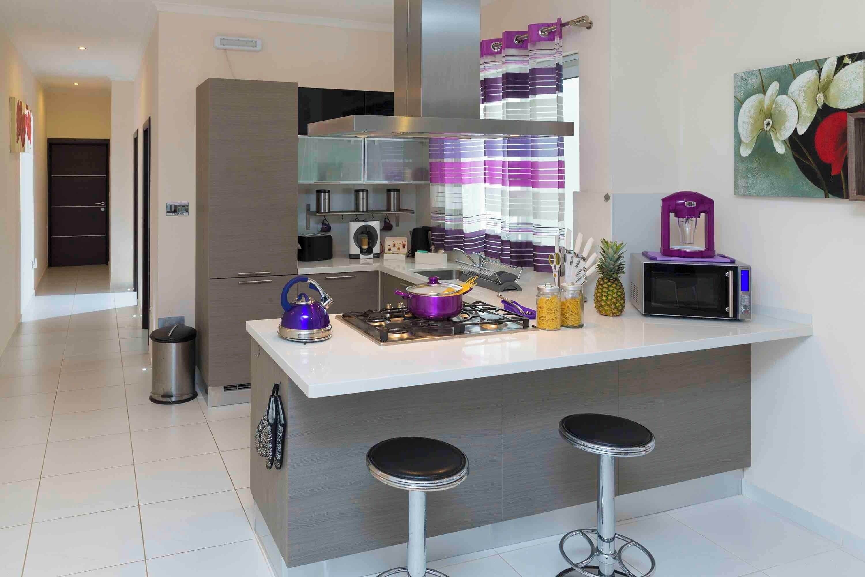 Una cocina moderna con una isla central, electrodomésticos de acero inoxidable y un microondas.