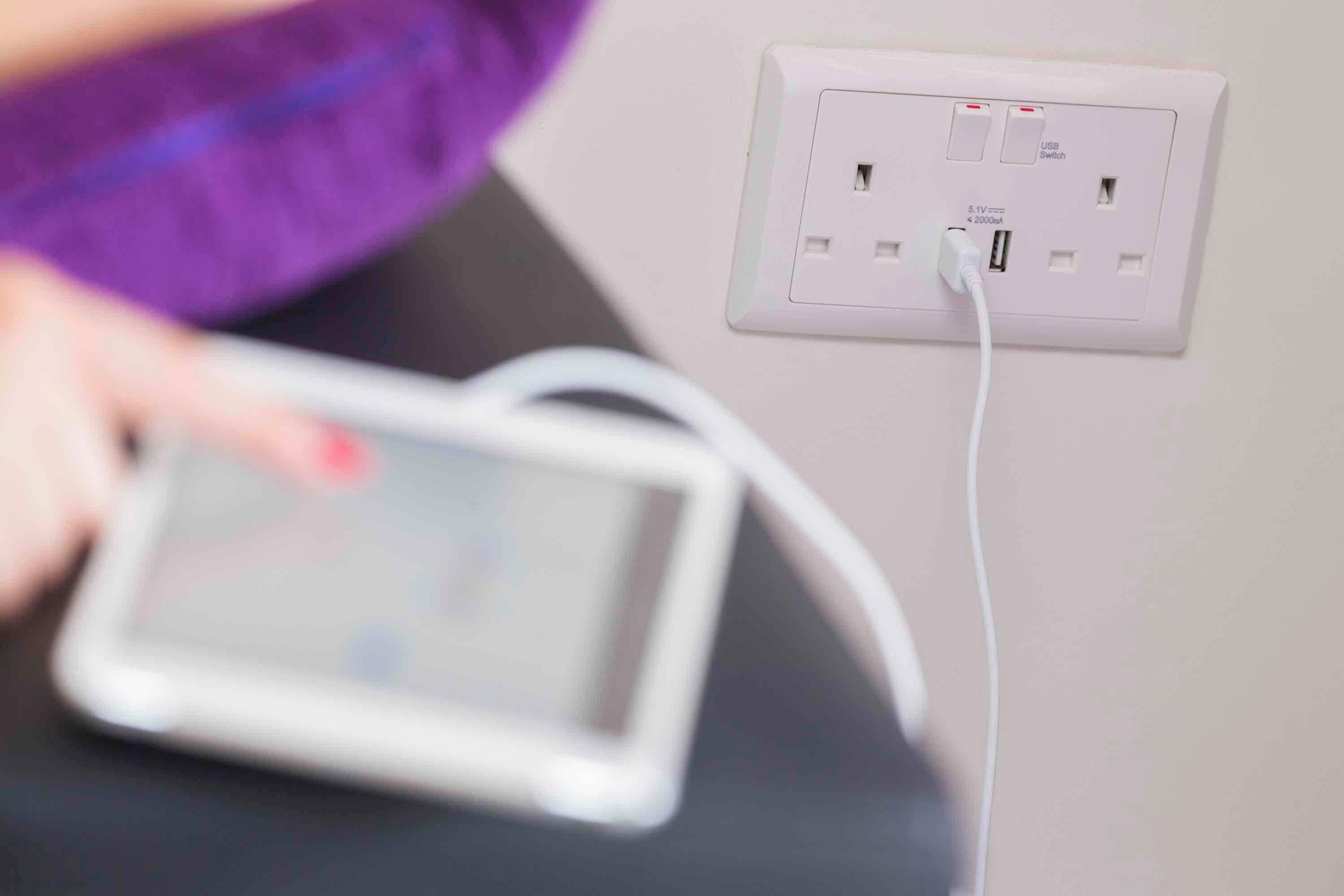 A tablet connected to a power outlet with a USB port and a switch.