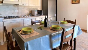 Cocina compacta con una mesa de comedor preparada para cuatro personas, un microondas y una estufa.