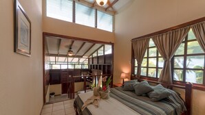 Quarto com uma cama grande, uma escrivaninha e vista para o exterior.