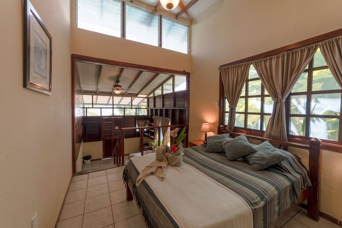 A bedroom with a large bed, a desk, and a view of the outdoors.