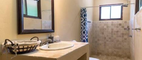 A bathroom with a sink, mirror, and shower.