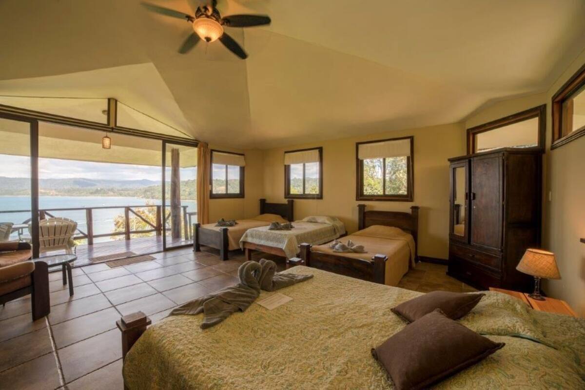 A bedroom with two beds, a large window, and a view of the outdoors.