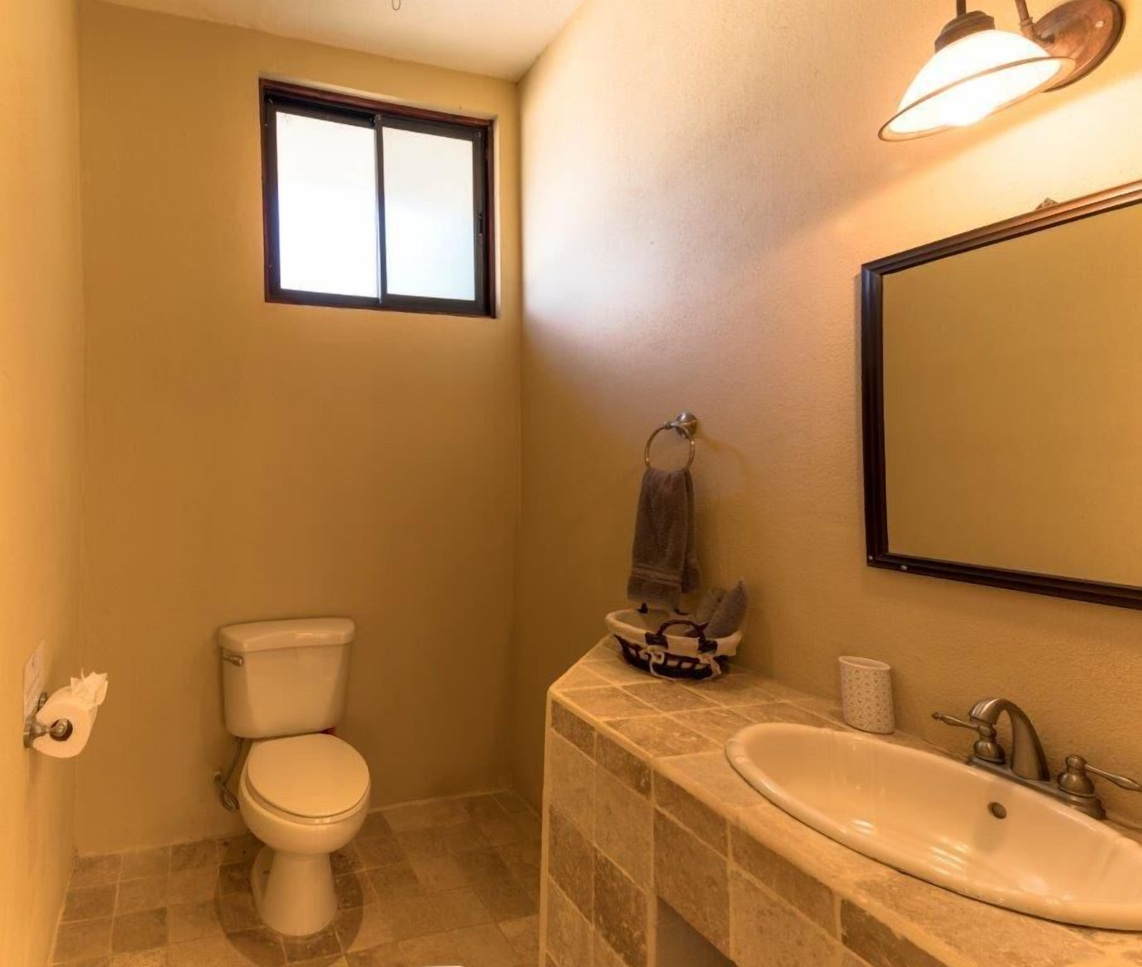 A bathroom with a toilet, sink, and window.