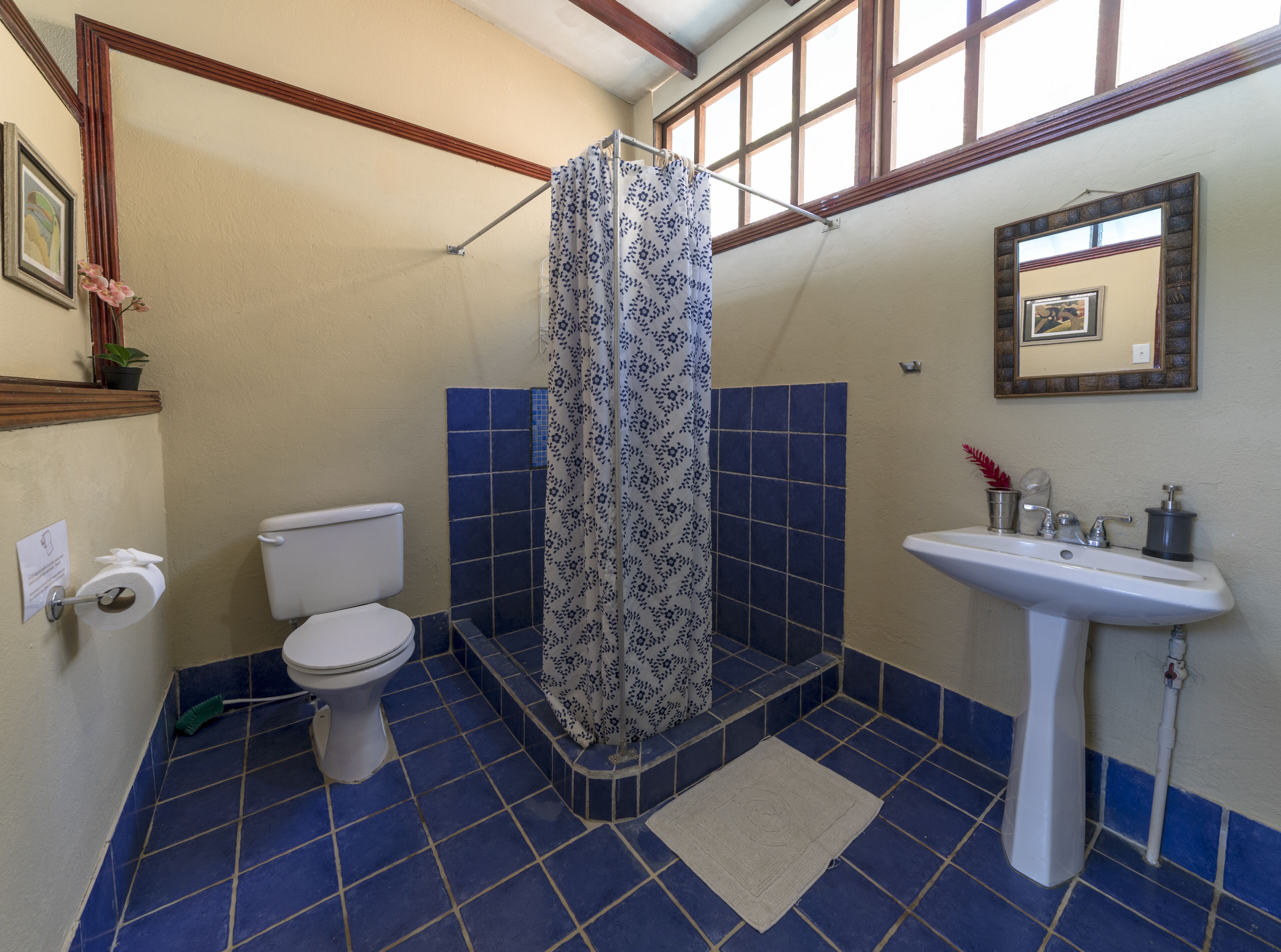 Ein Badezimmer mit Toilette, Dusche, Waschbecken und blau gefliestem Boden.