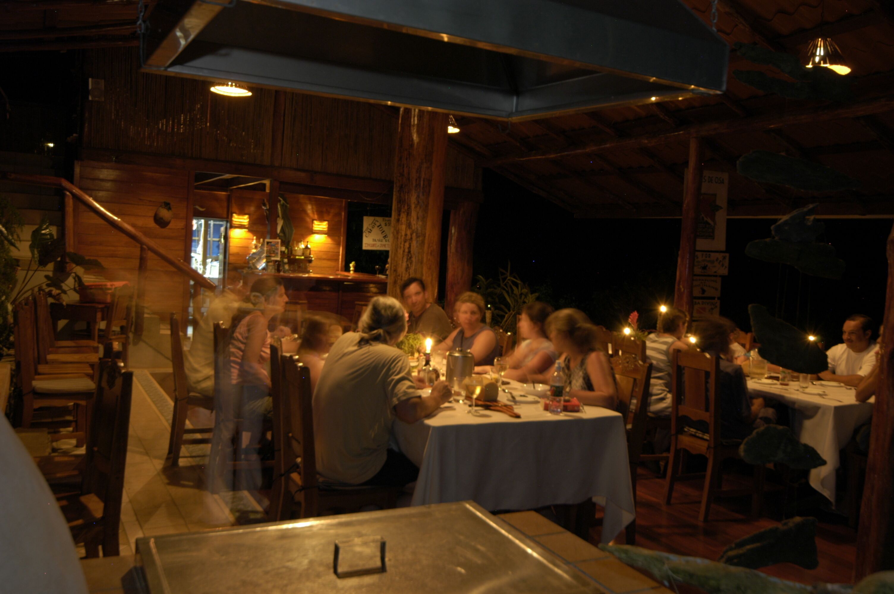 A restaurant with wooden interiors, tables set for dining, and a bar area.
