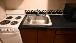 A kitchen with a stove, sink, and microwave. - Airport Motel (Pasco)