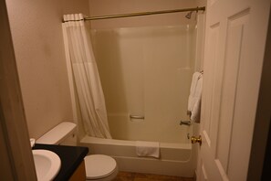 Habitación básica doble | Baño | Tina con regadera, regadera tipo lluvia, toallas, jabón