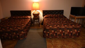 A hotel room with two beds, a lamp, a television, and a small table. - Airport Motel (Pasco)