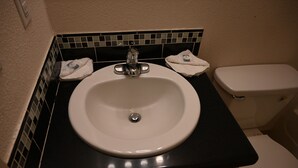 A bathroom with a white sink, black countertop, and a white toilet. - Airport Motel (Pasco)