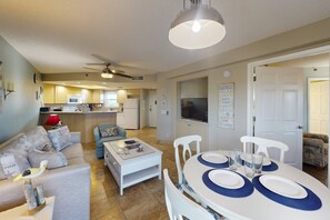 A modern living room with a sofa, coffee table, and dining table set for six.