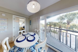 Enjoy meals with a view of palm trees and a clear sky from this open-plan living area with a dining table for four.