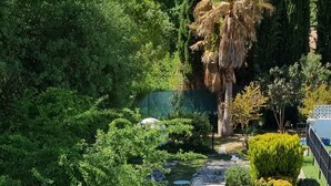 A garden with a gravel path, seating area, and various plants.