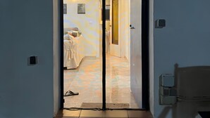 A doorway leading to a room with a bed, a nightstand, and a wall-mounted light fixture.
